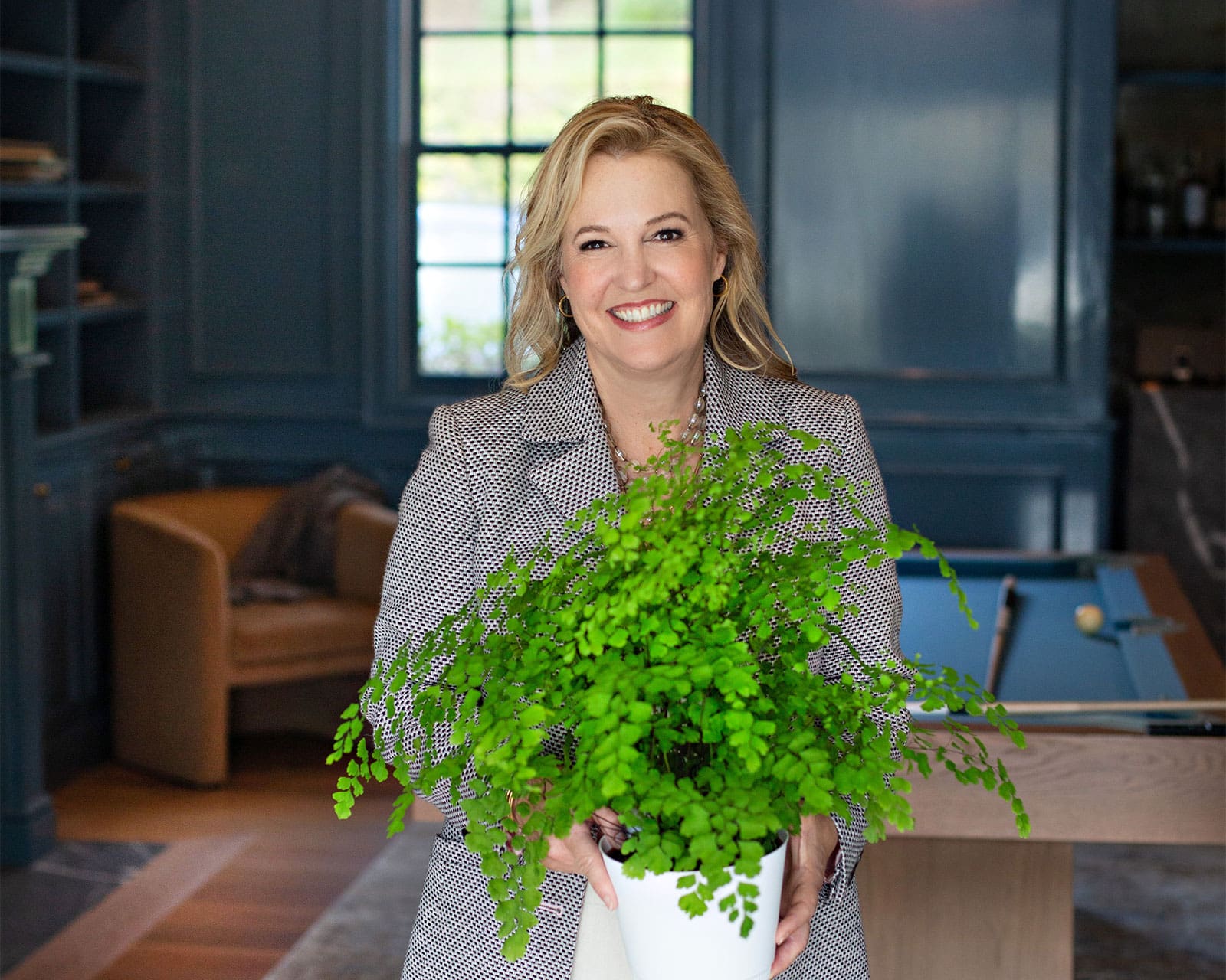 Cindi holding a fern in a house she is staging to sell - Buy or sell with confidence with Cindi Gortner